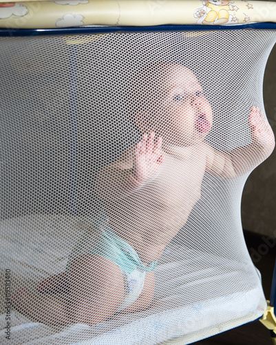 Baby in a diaper in playpen