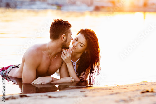 happy young couple having fun, man and woman in the sea on the beach. vintage retro style with soft focus and sun flare