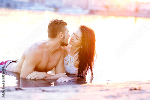 happy young couple having fun, man and woman in the sea on the beach. vintage retro style with soft focus and sun flare