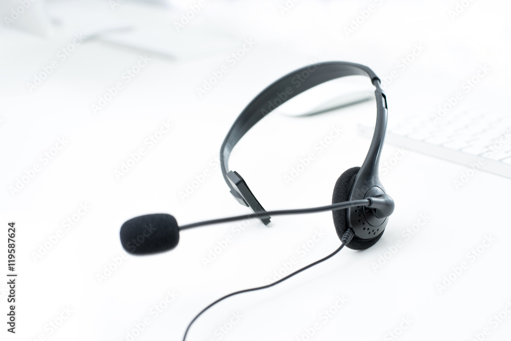 Microphone headset on white table with blur computer keyboard background Microphone headset on white table with blur computer keyboard background