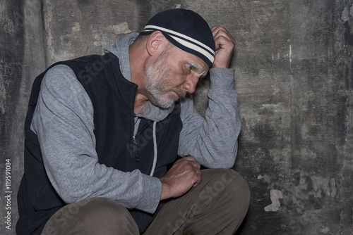 Portrait image of a mature man looking upset and worried on a stone background 