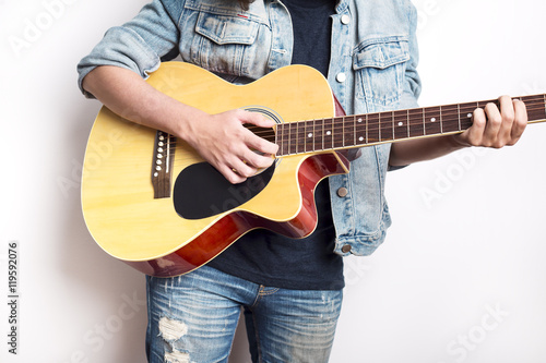 Portrait of a teenager playing guitar in studio wearing jeans jacket