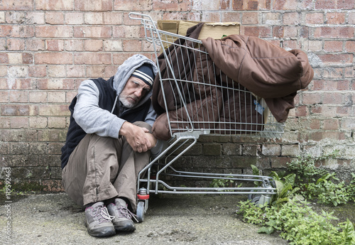 Homeless man out on the streets with his belongings in a trolley.