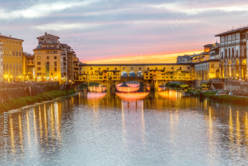 Illuminated cityscape view on Arno river with famous Ponte Vecchio bridge and buildings on the riverside on the sunset in Florence © rh2010