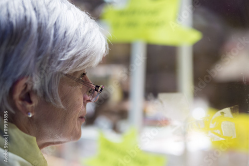 Seniorin an einem Schaufenster
