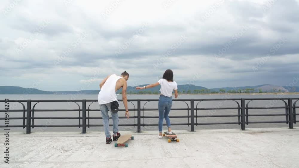 the guy with the girl riding on the promenade in long boards the guy with the girl riding on the promenade in long boards