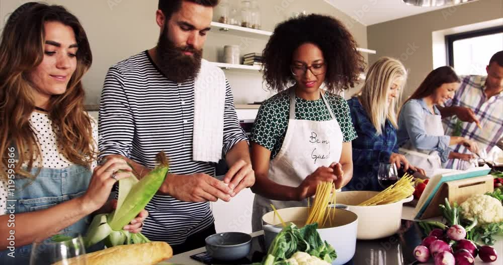Group of multi racial friends cooking dinner in a kitchen