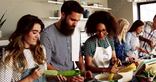 A Group of friends preparing dinner in a kitchen cooking and frying on pots and pans