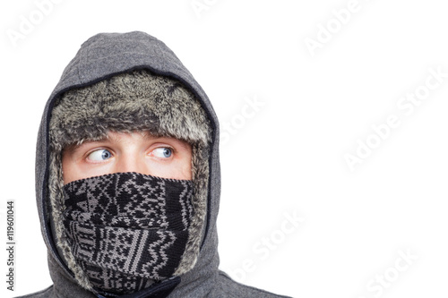 Young man in hat, scarf and hood hiding from the cold weather in the winter