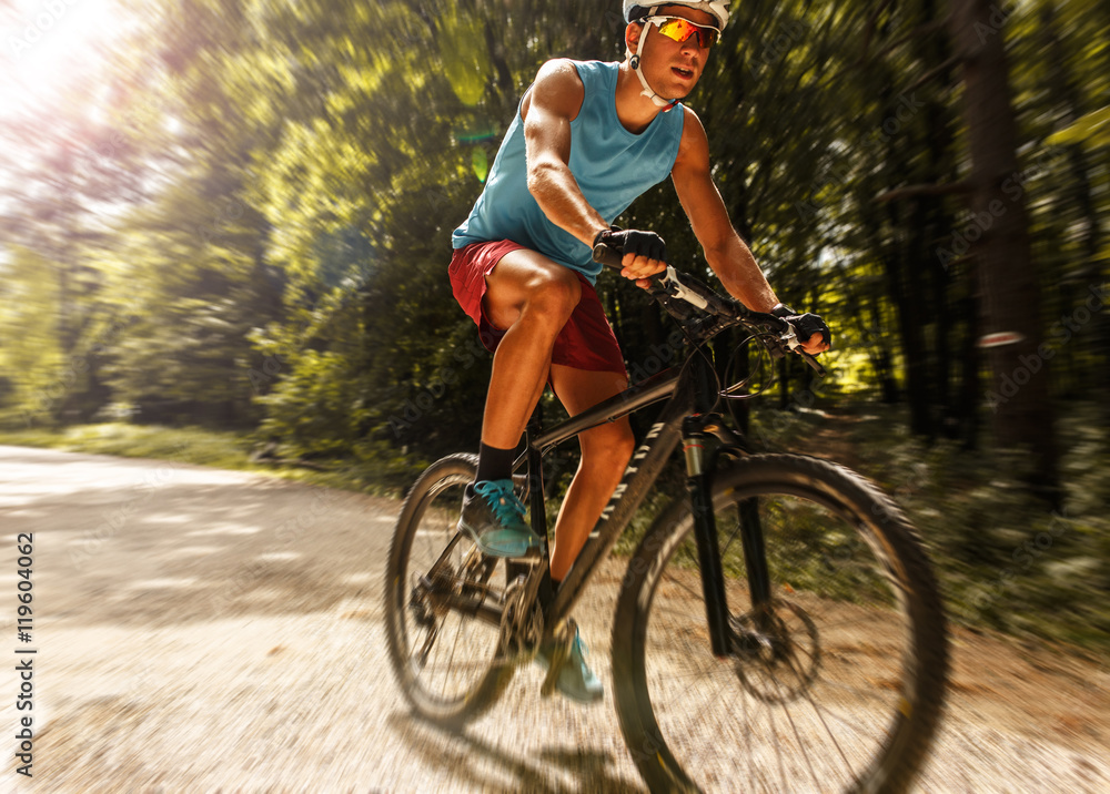 Fototapeta premium Young man riding a mountain bike on old country road.