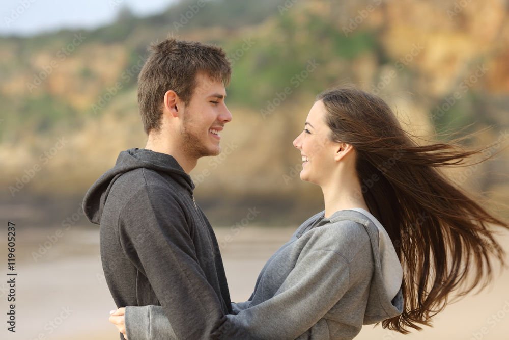 Happy teenager couple hugging and facing Happy teenager couple hugging and facing