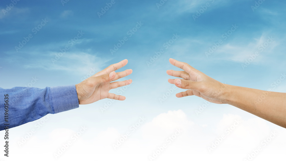 Hands reaching together on blue sky background Hands reaching together on blue sky background