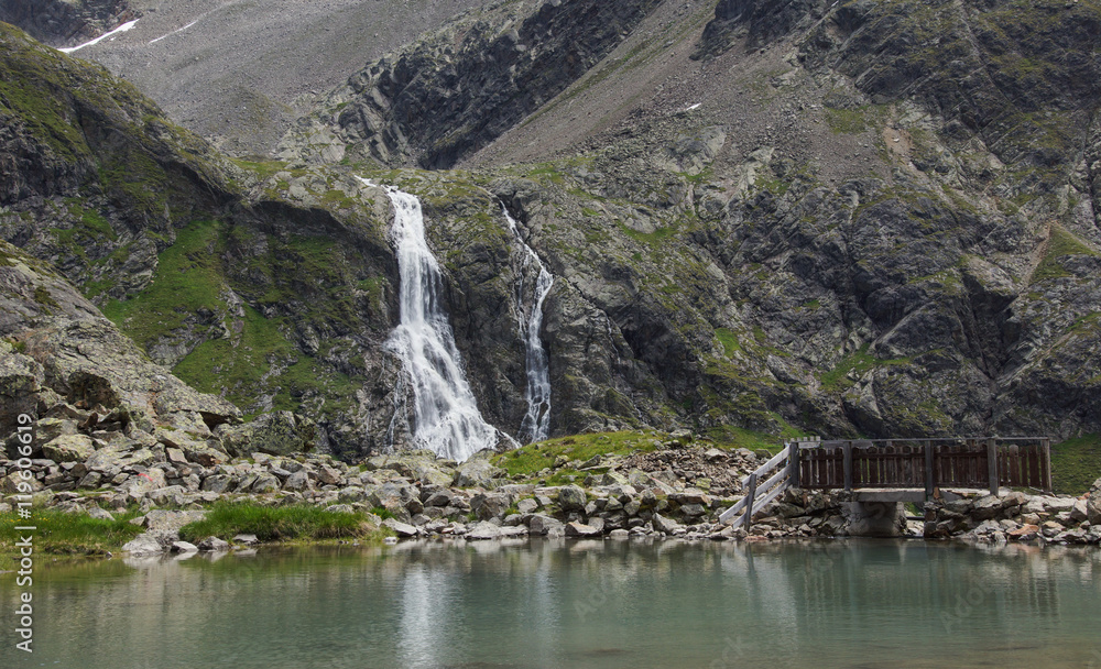 Bergsee mit Wasserfall und Brücke