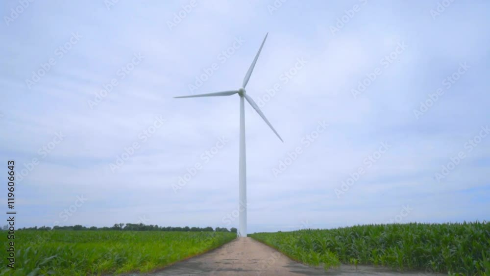 Wind turbine on wind farm. Wind generator. Wind power generation. Wind turbine generator standing on rustic road between farm fields. Renewable energy concept. Sustainable energy resource Wind turbine on wind farm. Wind generator. Wind power generation. Wind turbine generator standing on rustic road between farm fields. Renewable energy concept. Sustainable energy resource