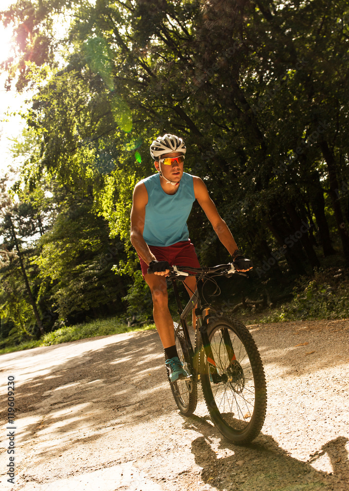 Fototapeta premium Young man riding a mountain bike on old country road.