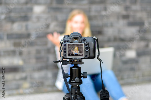 Young woman on camera LCD screen waving