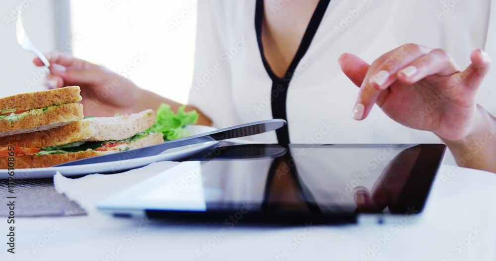 Woman eating lunch and using tablet computer Woman eating lunch and using tablet computer