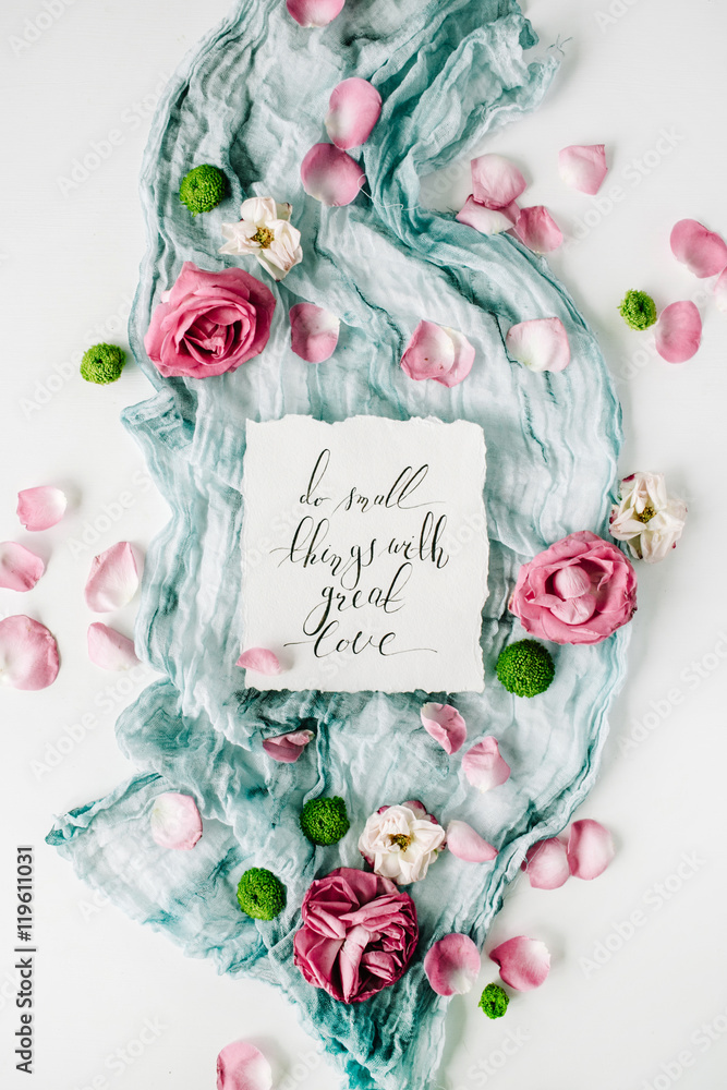 inspirational quote written in calligraphy style on paper with red roses, pink petals and blue textile on white background. Flat lay, top view inspirational quote written in calligraphy style on paper with red roses, pink petals and blue textile on white background. Flat lay, top view