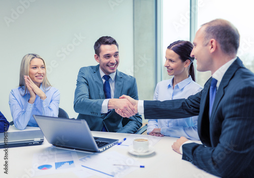 two businessman shaking hands in office