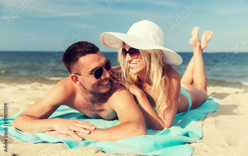 happy couple in swimwear lying on summer beach