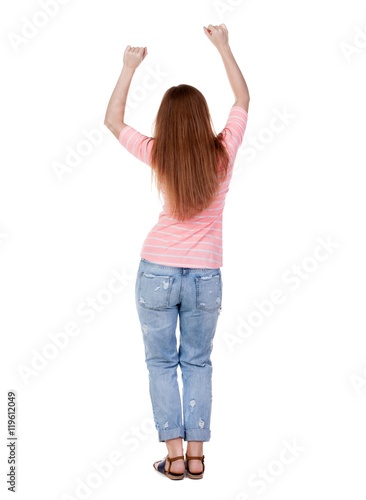 Back view of joyful woman celebrating victory hands up. Rear view people collection. backside view of person. Isolated over white background. slender redhead in a jeans shows symbol of success or