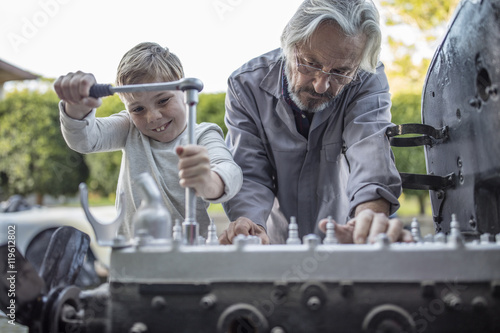 Senior man and boy working on mechanism of a car
