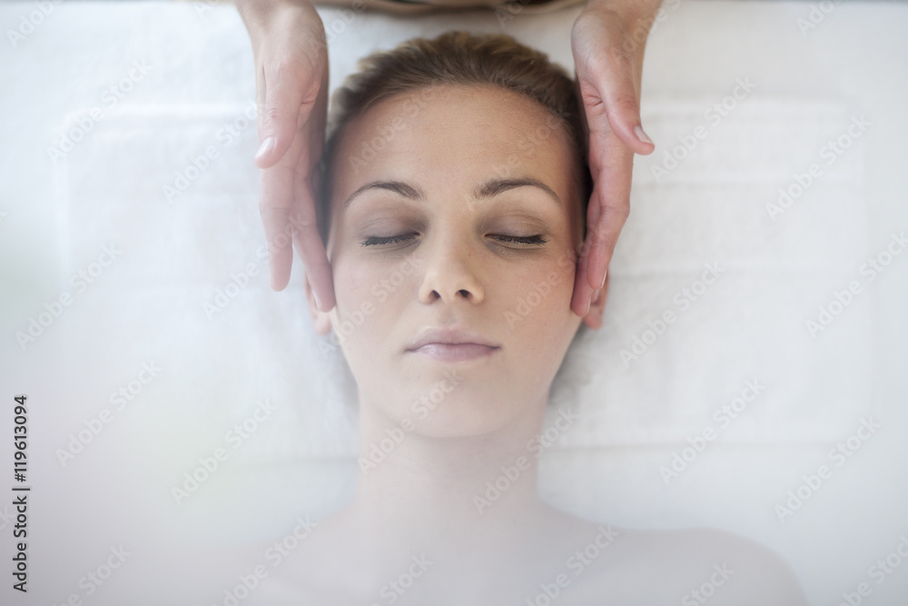 Young woman lying on massage table receiving beauty treatment
