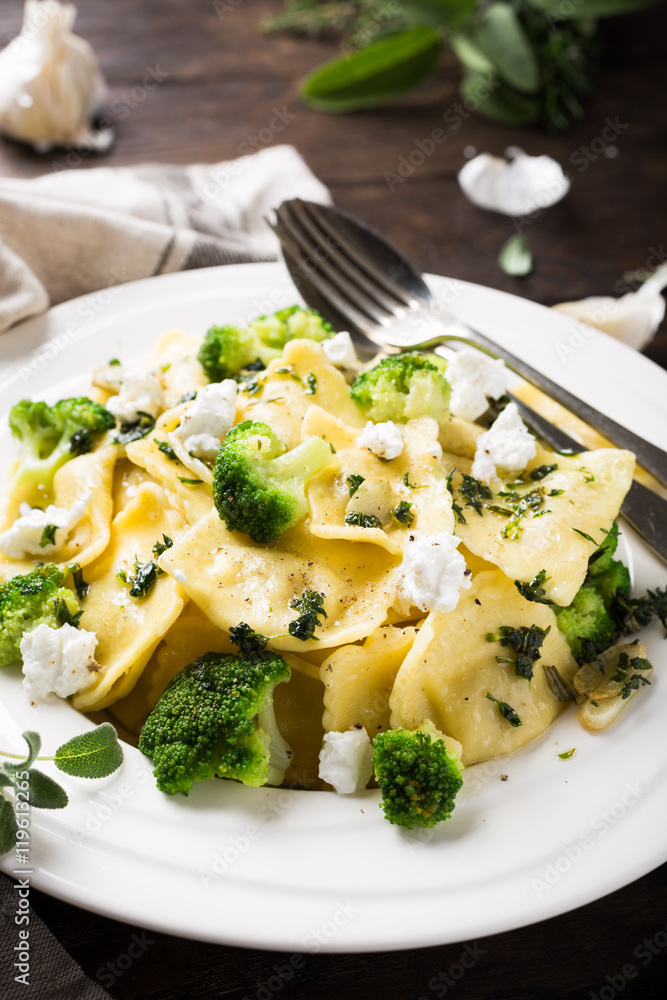 Plate of ravioli with broccoli, goat cheese and herbs on old wooden background. Italian healthy food concept. Plate of ravioli with broccoli, goat cheese and herbs on old wooden background. Italian healthy food concept.