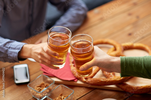 close up of hands clinking beer at bar or pub