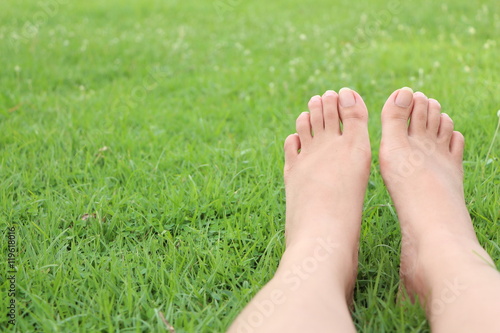 A woman sitting barefoot, relax on the grass.