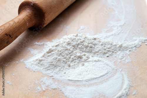 Wooden rolling pin with flour on wooden desk
