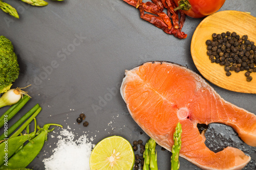 Fresh raw salmon filet with spicy herbs on black plate