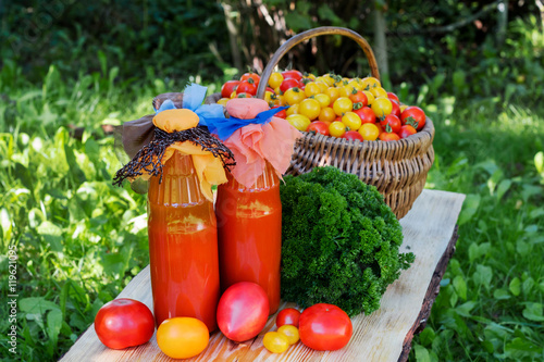 Tomato juice with parsley in a bottle on wooden table, rustic. 