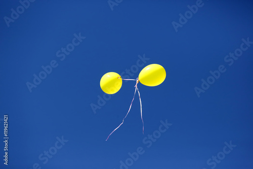 two yellow balloon against a blue sky