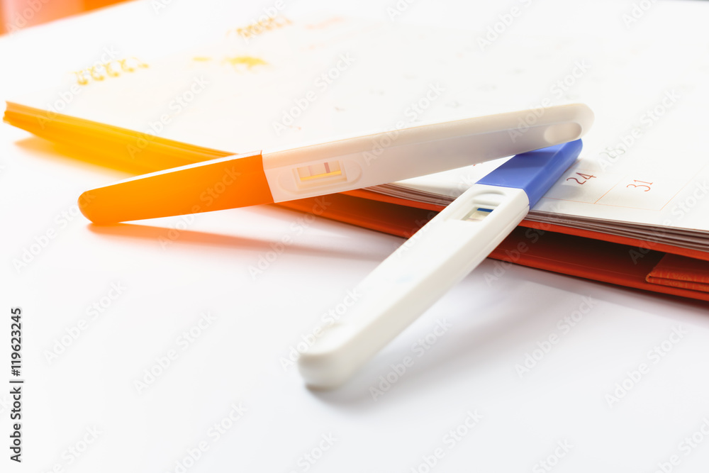 Pregnancy test with positive result lying on calendar background Pregnancy test with positive result lying on calendar background