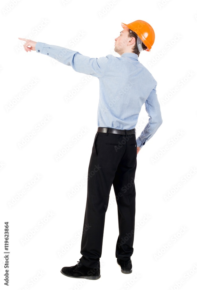 Back view of pointing young men in helmet. Curly businessman in a light jacket and a helmet shows his hand forward. Back view of pointing young men in helmet. Curly businessman in a light jacket and a helmet shows his hand forward.