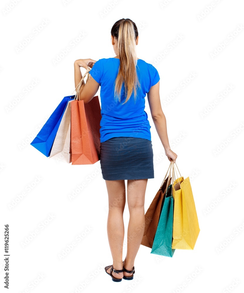 back view of woman with shopping bags. backside view of person. girl in a short skirt and a blue shirt holding paper bags.