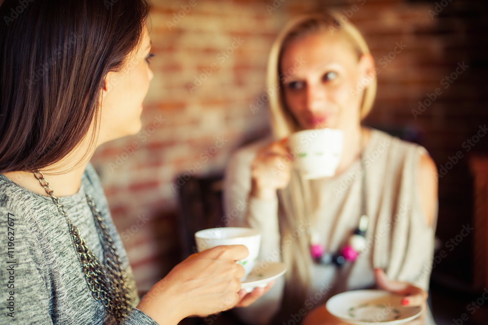 Two young female friends gossiping in a bar Two young female friends gossiping in a bar