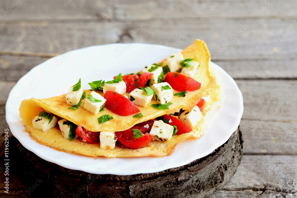 Fried omelet stuffed with cheese, tomatoes and parsley. Stuffed omelette on a plate and on old wooden background. Easy egg omelet recipe. Closeup