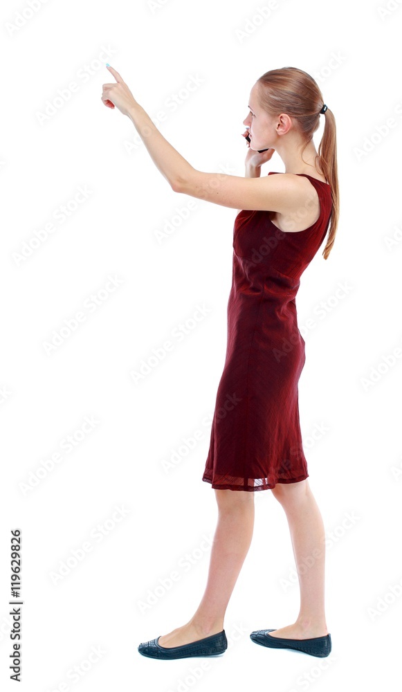 back view of pointing young beautiful girl with tablet computer. girl watching. Isolated over white background. The girl in the maroon sleeveless dress goes sideways and talking on a smartphone and back view of pointing young beautiful girl with tablet computer. girl watching. Isolated over white background. The girl in the maroon sleeveless dress goes sideways and talking on a smartphone and
