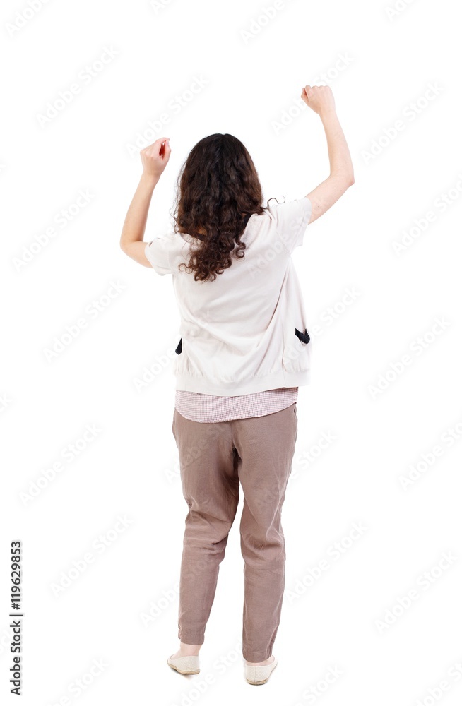 back view of dancing young beautiful woman. Long-haired curly girl happily waving his hands. back view of dancing young beautiful woman. Long-haired curly girl happily waving his hands.