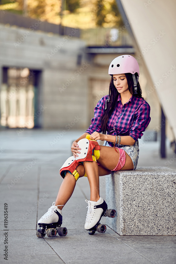 Young sporty woman and skating protection equipment. Beautiful girl puts on  protective gear for rollerblading. Stylish pink skating helmet, knee pads  and quad roller skate. Stock Photo | Adobe Stock