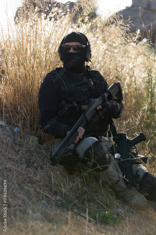 Man with rifle sitting in grassy field Man with rifle sitting in grassy field