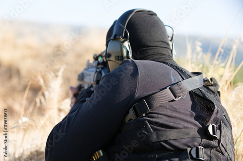 Man with rifle aiming in grassy field © eric