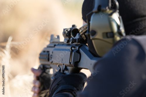 Close up of man with rifle aiming in grassy field
