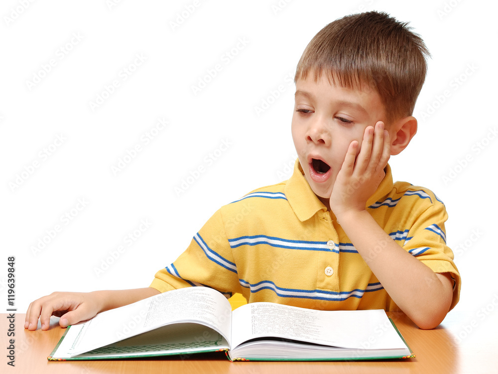 Sleepy boy reads book isolated on white background Sleepy boy reads book isolated on white background