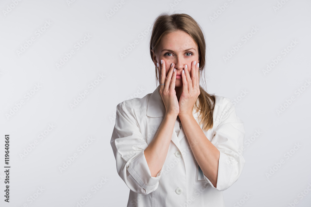 Young female doctor or nurse is shocked with hands on her mouth Young female doctor or nurse is shocked with hands on her mouth