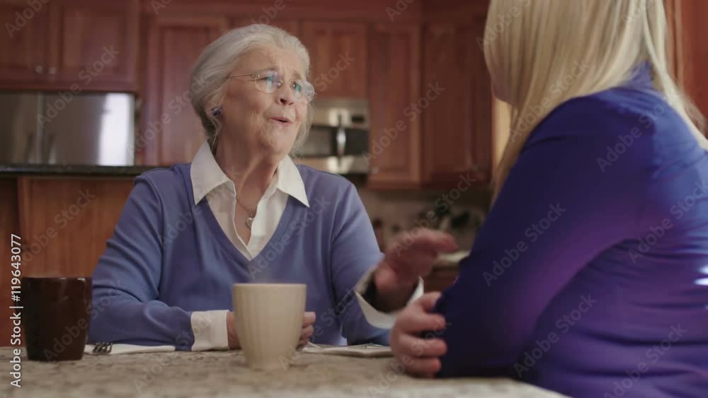 An elderly senior woman enjoys talking with a friend while drinking coffee. Shot in 4K UHD. An elderly senior woman enjoys talking with a friend while drinking coffee. Shot in 4K UHD.