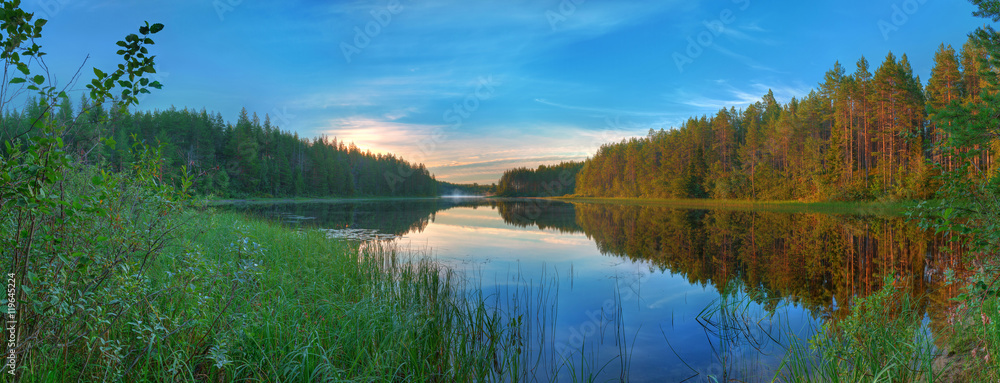 Panoramic beautiful landscape of the lake surrounded by forest at dawn.