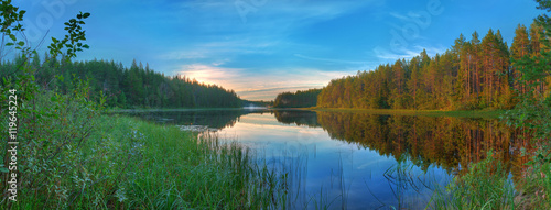 Panoramic beautiful landscape of the lake surrounded by forest at dawn.